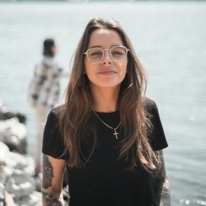 woman in black crew neck t-shirt wearing brown framed eyeglasses standing on rocky shore during